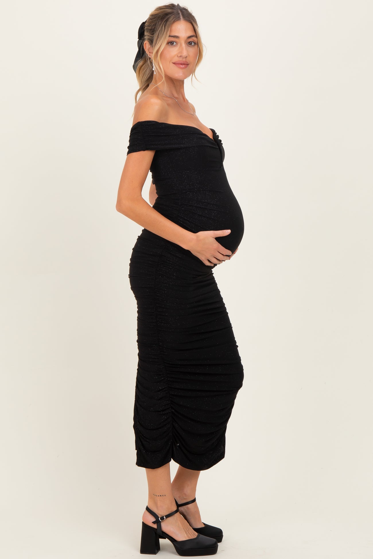 woman wearing a black off-the-shoulder maternity dress with ruching and a visible baby bump