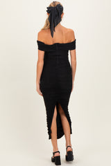 woman wearing a black off-shoulder maternity dress with ruched detailing and a side slit, showing a baby bump