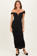 woman wearing a black off-the-shoulder fitted evening dress with a ruched design and plunging neckline