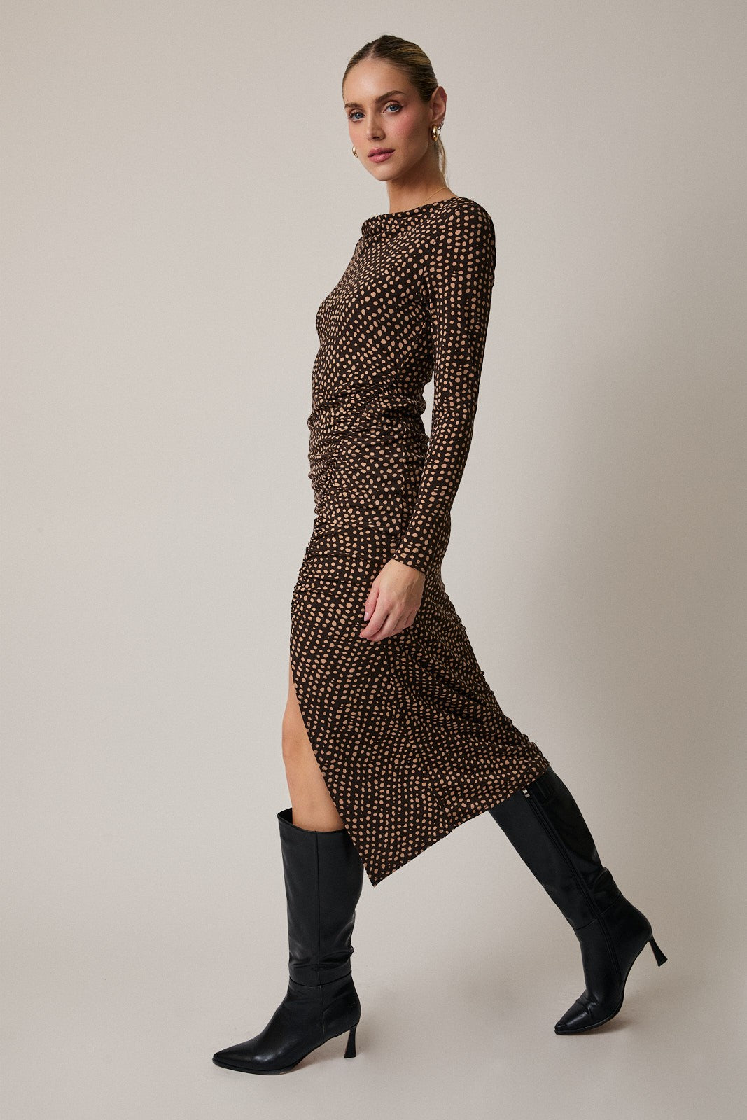 woman wearing a brown long sleeve printed dress with a side slit and black knee-high boots