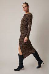 woman wearing a brown long sleeve printed dress with a side slit and black knee-high boots