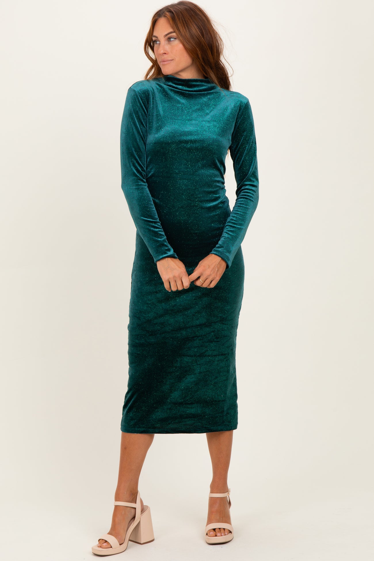 woman wearing a green velvet long sleeve midi dress with a high neck and form-fitting silhouette