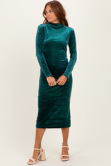 woman wearing a green velvet long sleeve midi dress with a high neck and form-fitting silhouette