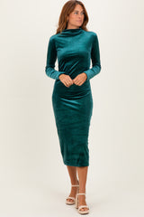 woman wearing a teal long sleeve velvet midi dress with a high neckline and a fitted silhouette