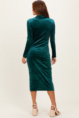 woman wearing a dark green velvet long sleeve midi dress, showing the back view with a fitted silhouette