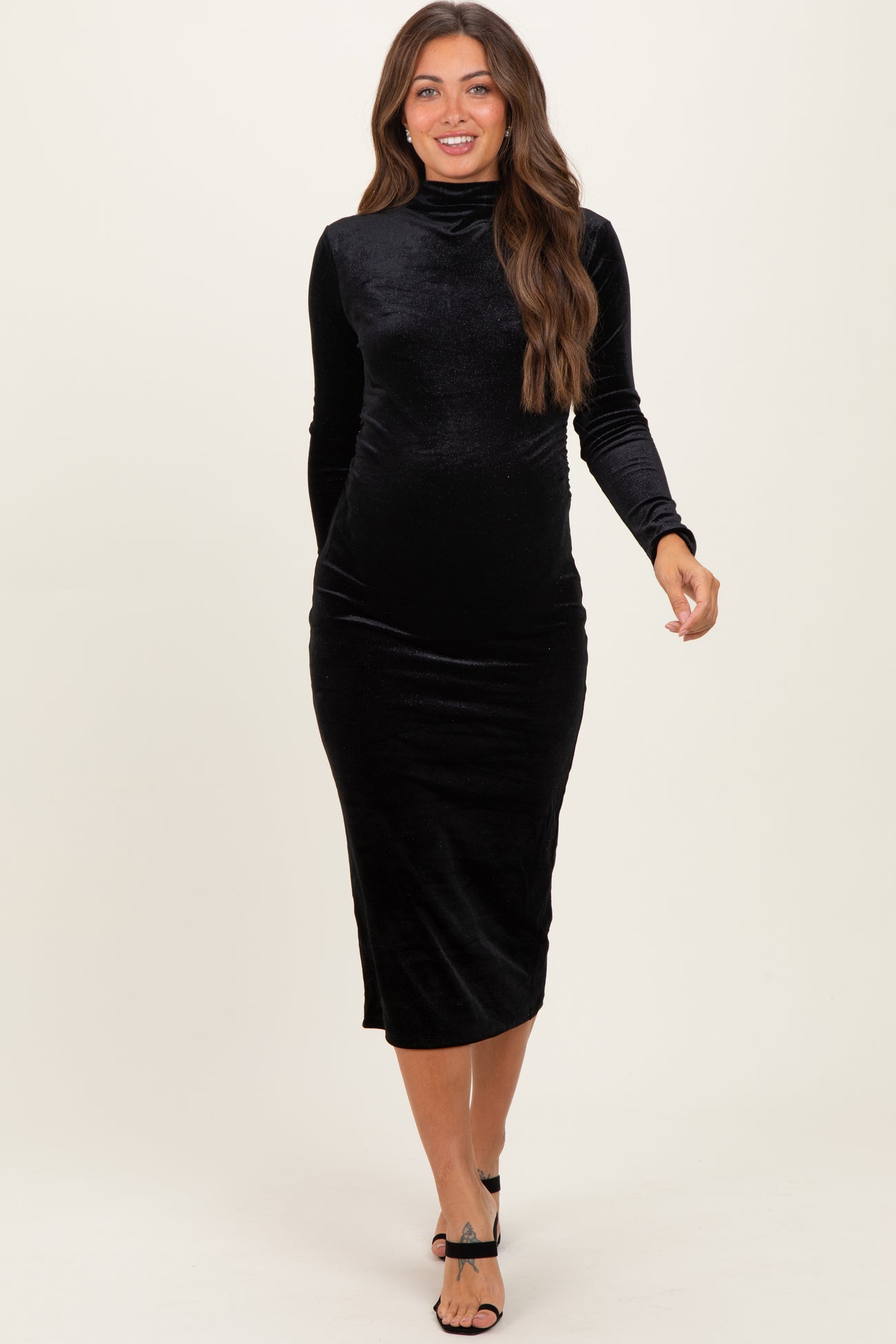 woman wearing a black velvet maternity dress with a high neck and long sleeves, showing her baby bump