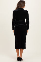 woman wearing a black velvet maternity dress with long sleeves and a fitted silhouette, showing a baby bump