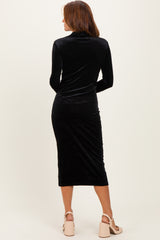 woman wearing a black velvet long sleeve midi dress with a fitted silhouette and a high neck