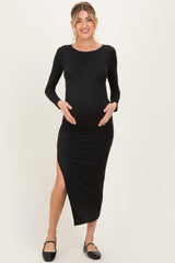 woman wearing a black long sleeve maternity dress with a slit, holding her baby bump