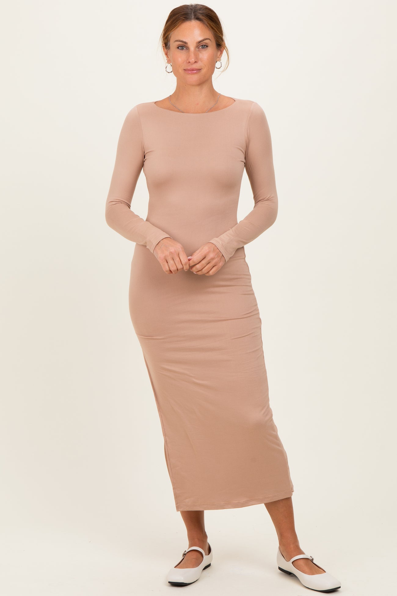 woman wearing a fitted beige long sleeve maxi dress with a scoop neckline and slim silhouette