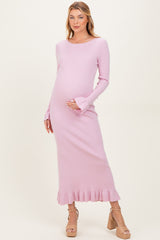 woman wearing a light pink ribbed maternity dress with long sleeves and ruffled hem, gently cradling her baby bump