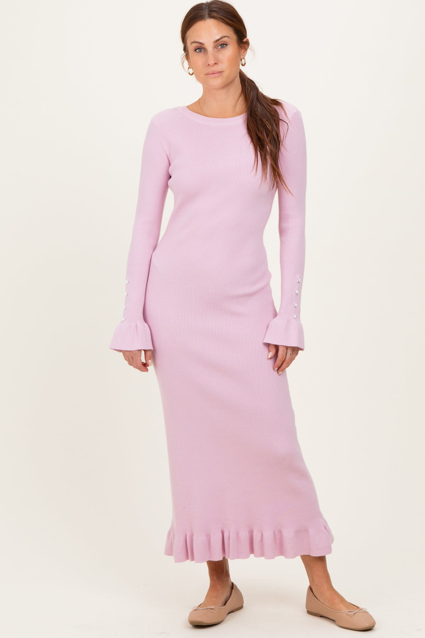 woman wearing a light pink ribbed long sleeve dress with bell sleeves and ruffle hem