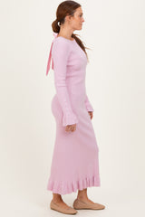 woman wearing a long pink ribbed knit dress with flared sleeves and a bow detail at the back