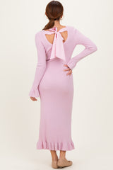 woman wearing a pink long sleeve ribbed knit dress with a back cutout and bow detail, styled with ruffled hem