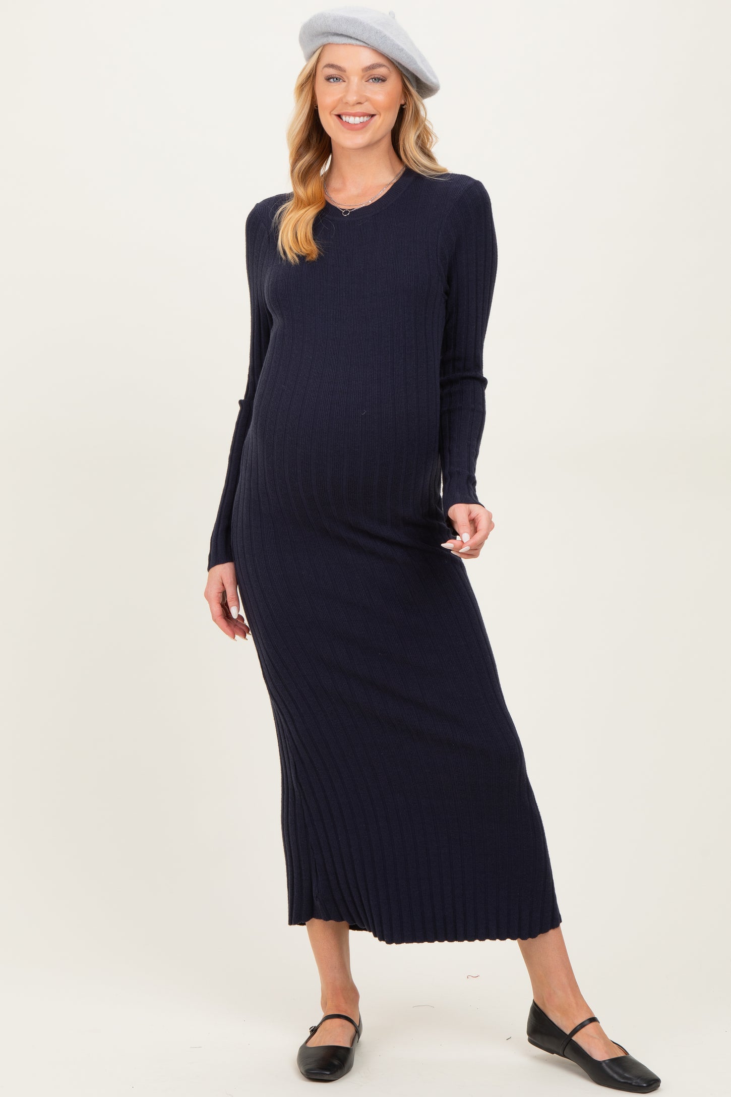 woman wearing a navy ribbed maternity maxi dress and a beret, showcasing her baby bump