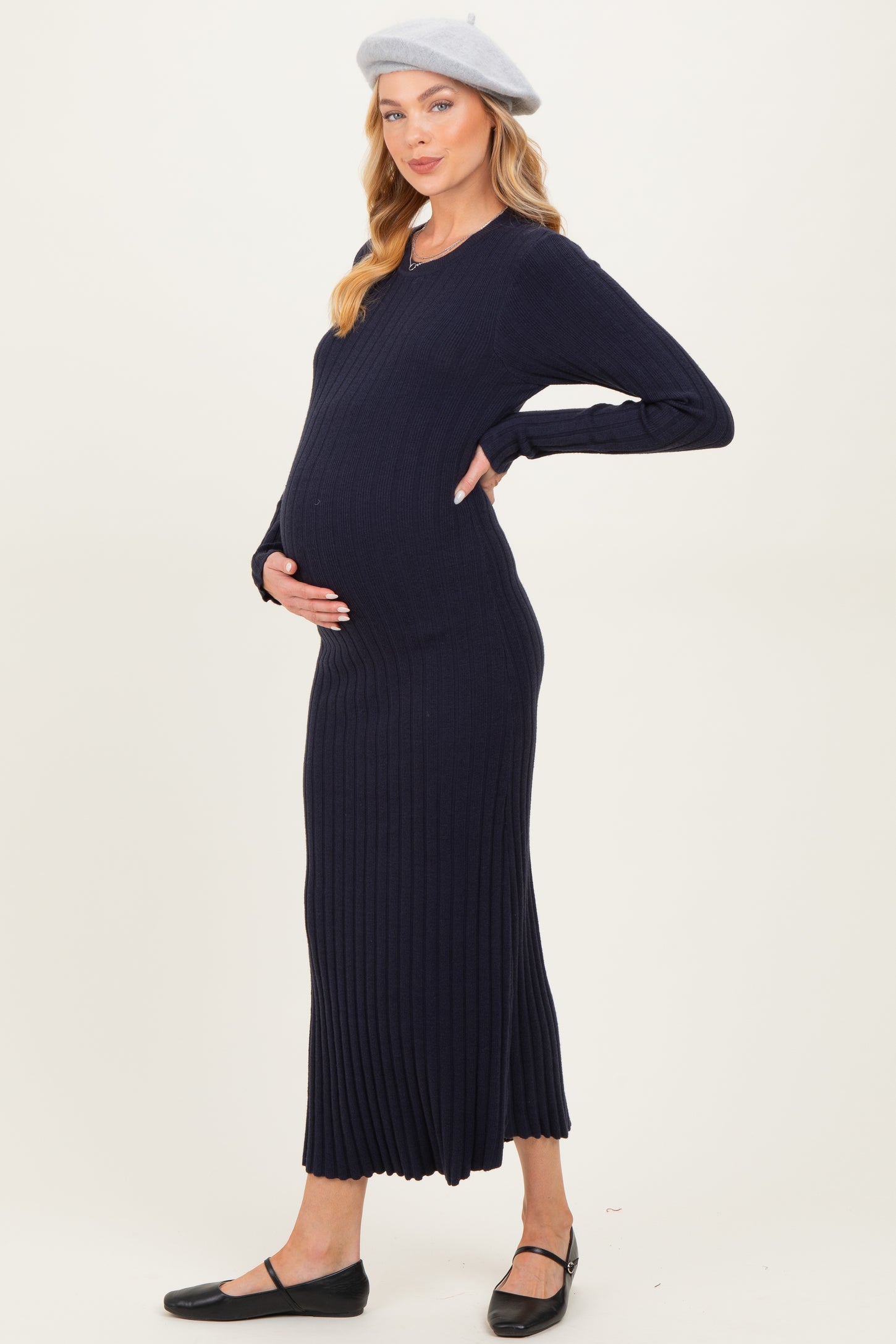 woman wearing a navy blue ribbed maternity dress and holding her baby bump