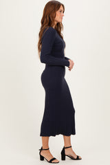 woman wearing a navy blue ribbed long sleeve midi dress with a scalloped hem and strappy black heels