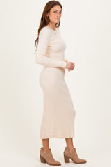 woman wearing a beige ribbed midi dress with long sleeves, side slit, and paired with ankle boots
