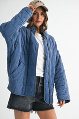 woman wearing a blue quilted jacket with pockets and a baseball cap, styled with a white t-shirt and black shorts