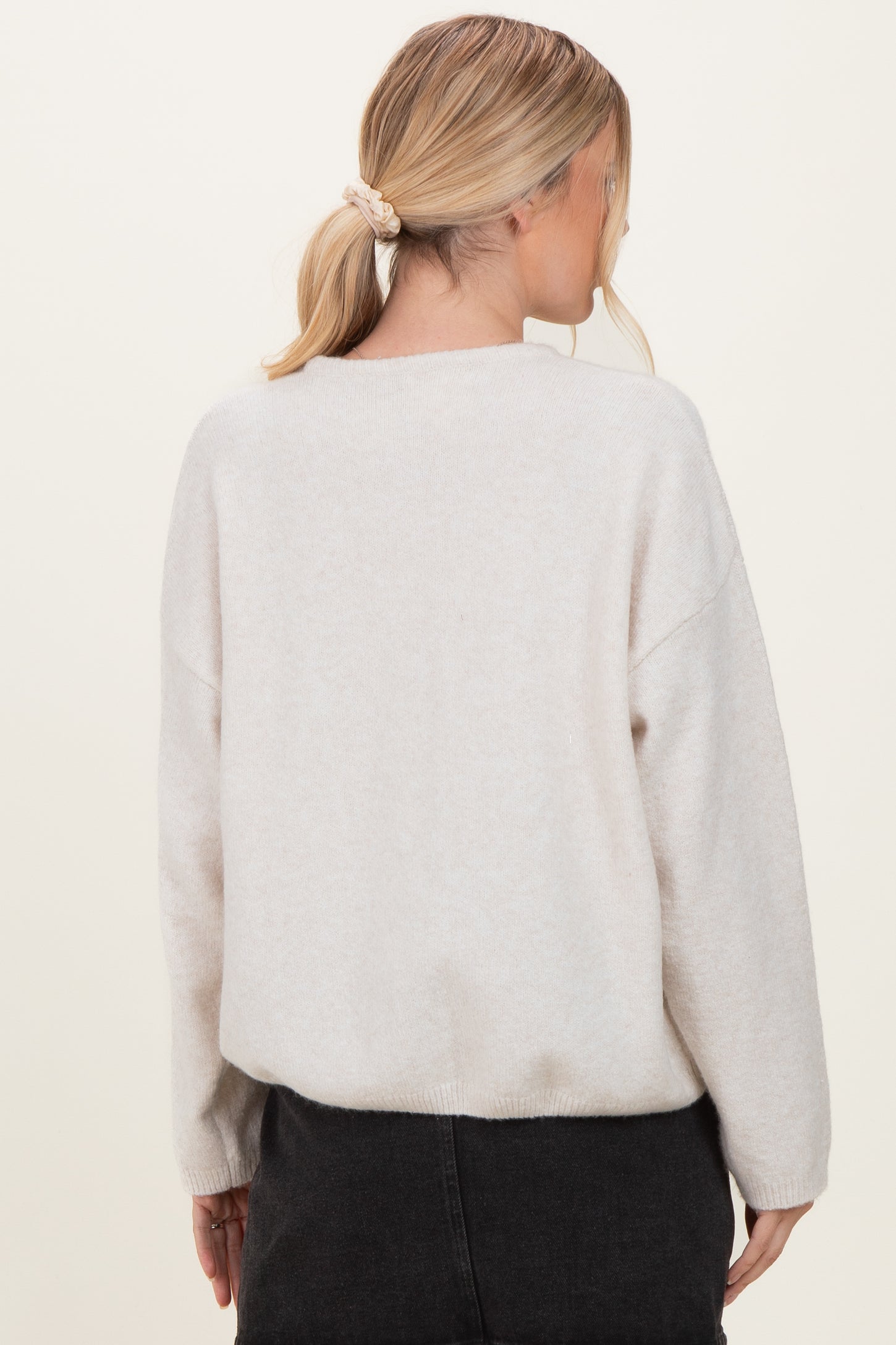 woman wearing a light beige oversized sweater with dropped shoulders, viewed from the back