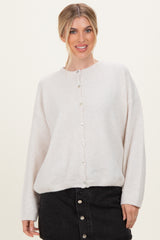 woman wearing a light beige oversized cardigan with pearl buttons and black denim skirt