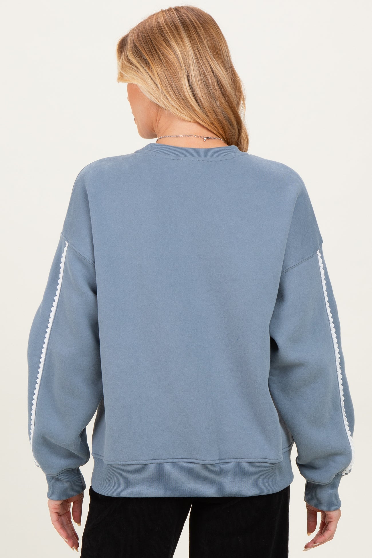 woman wearing a back view of a blue maternity sweatshirt with white detailing on the sleeves