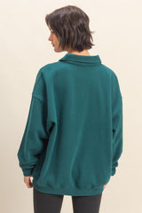 woman wearing a teal oversized sweatshirt with a collar, showing the back view and paired with black leggings