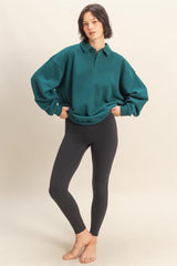 woman wearing an oversized teal polo sweatshirt paired with black leggings