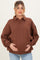 woman wearing a brown oversized maternity sweatshirt with a collar and holding her baby bump