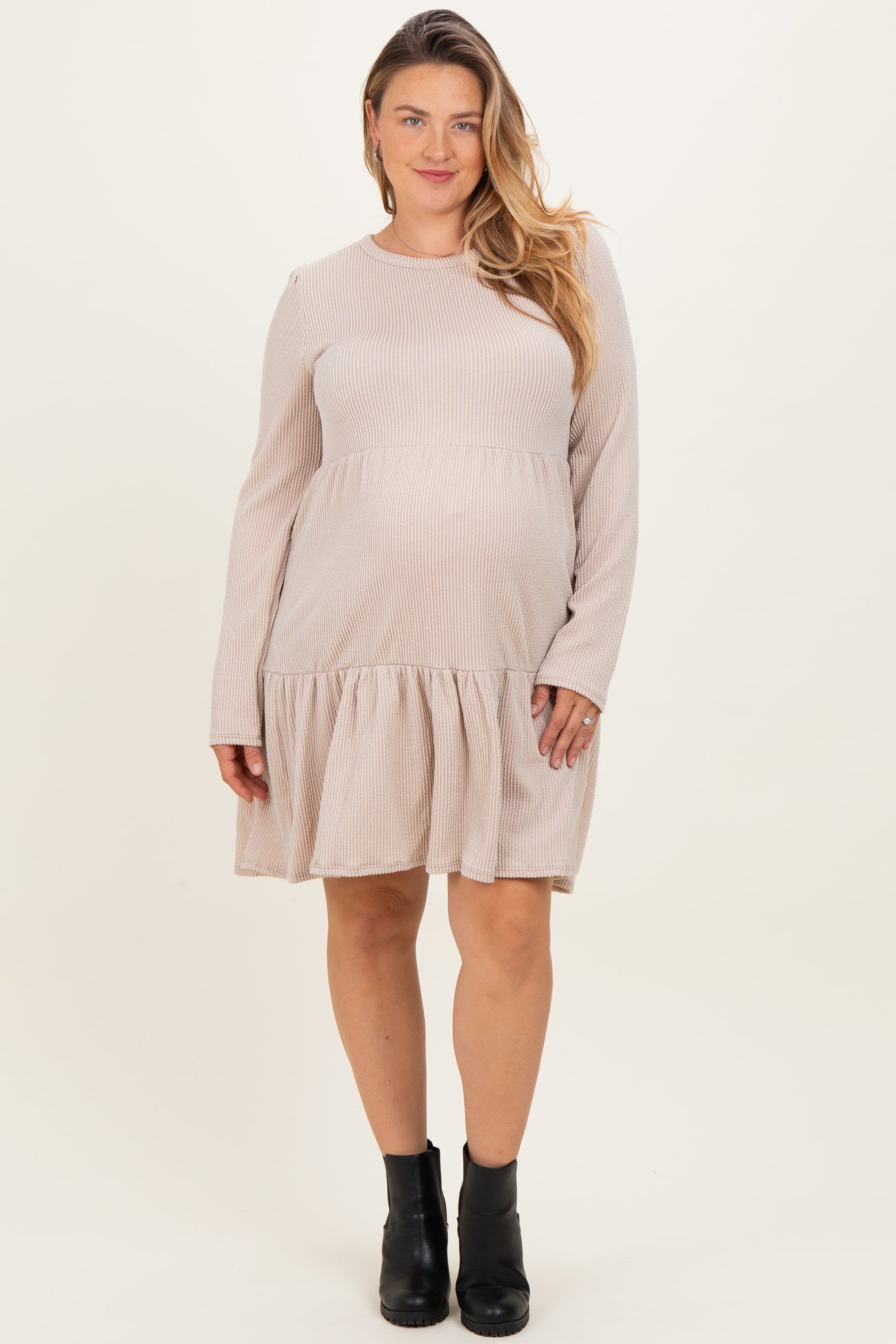woman wearing a beige ribbed long sleeve maternity dress with a flared hemline and visible baby bump