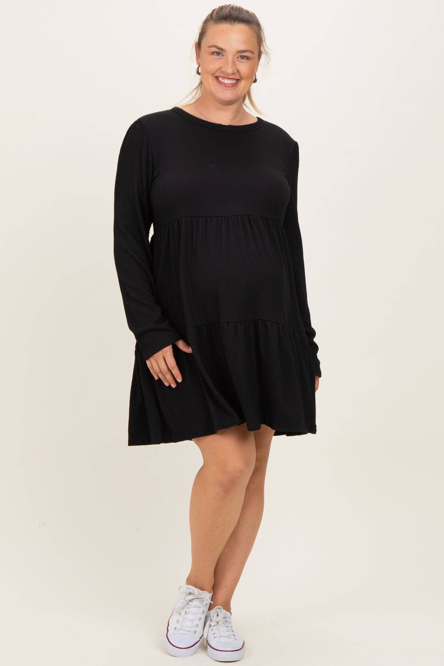 woman wearing a black ribbed long sleeve maternity dress with a layered skirt and a visible baby bump
