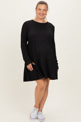woman wearing a black ribbed long sleeve maternity dress with a layered skirt and a visible baby bump