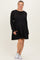 woman wearing a black ribbed long sleeve maternity dress with a layered skirt and a visible baby bump