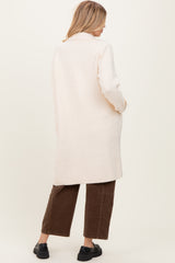 woman wearing a soft pink long coat with side pockets and brown wide-leg pants, viewed from the back