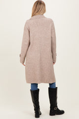 woman wearing a long beige cardigan, styled with blue jeans and black knee-high boots, shown from the back