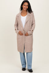 woman wearing a beige maternity coat with an open front and side buttons, holding her baby bump