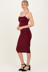 woman wearing a burgundy sparkly midi dress with ruching and thin straps, styled with black ankle-strap heels