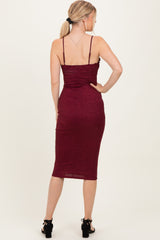 woman wearing a burgundy glitter midi dress with thin straps and a fitted silhouette, viewed from the back