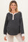 woman wearing a black and cream striped maternity top with button details and long sleeves, showcasing her baby bump