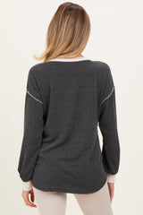 woman wearing a striped gray maternity top with long sleeves and contrasting cuffs, showing a relaxed fit from the back