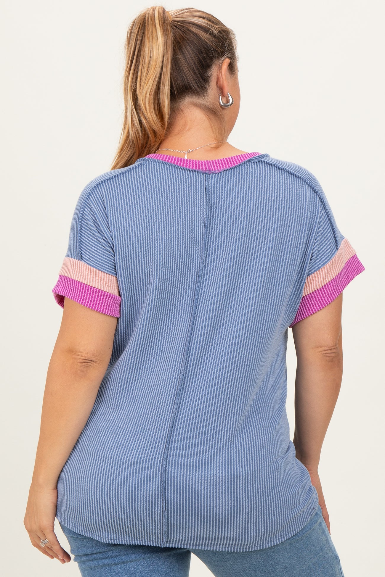 woman wearing a blue and pink striped maternity plus top from the back, featuring short sleeves and a relaxed fit
