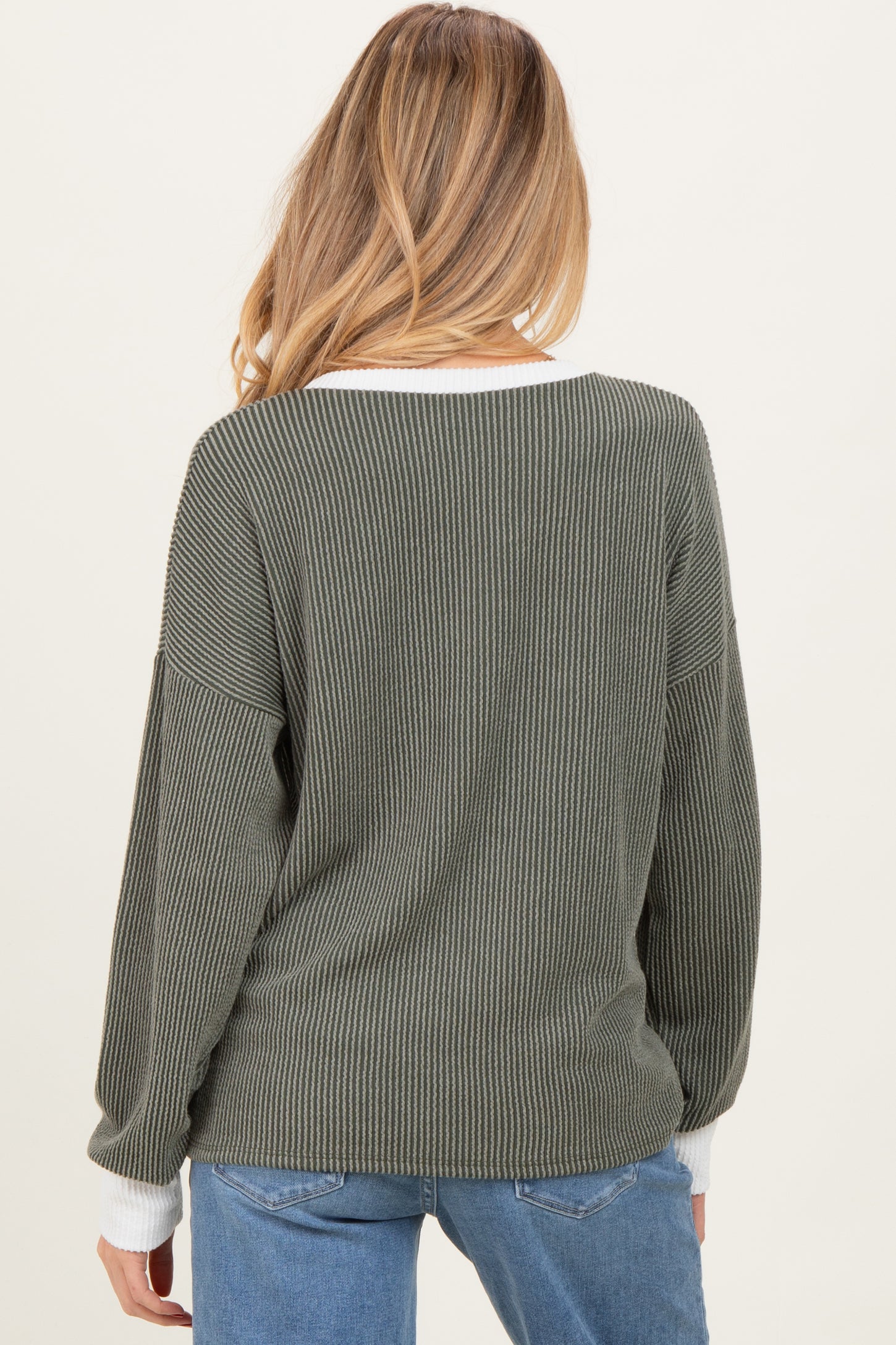 woman wearing an olive green ribbed maternity sweater with a white neckline, seen from the back