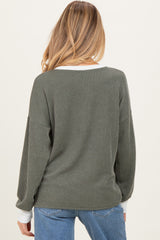 woman wearing an olive green ribbed maternity sweater with a white neckline, seen from the back