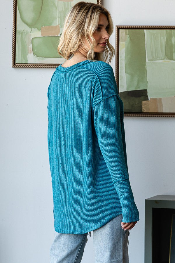 woman wearing a long sleeve teal ribbed top with a relaxed fit and slouchy silhouette