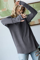woman wearing a loose-fitting gray ribbed long sleeve top with thumbholes and distressed jeans