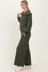 woman wearing a dark green ribbed zip-up hoodie and matching wide-leg pants with white sneakers