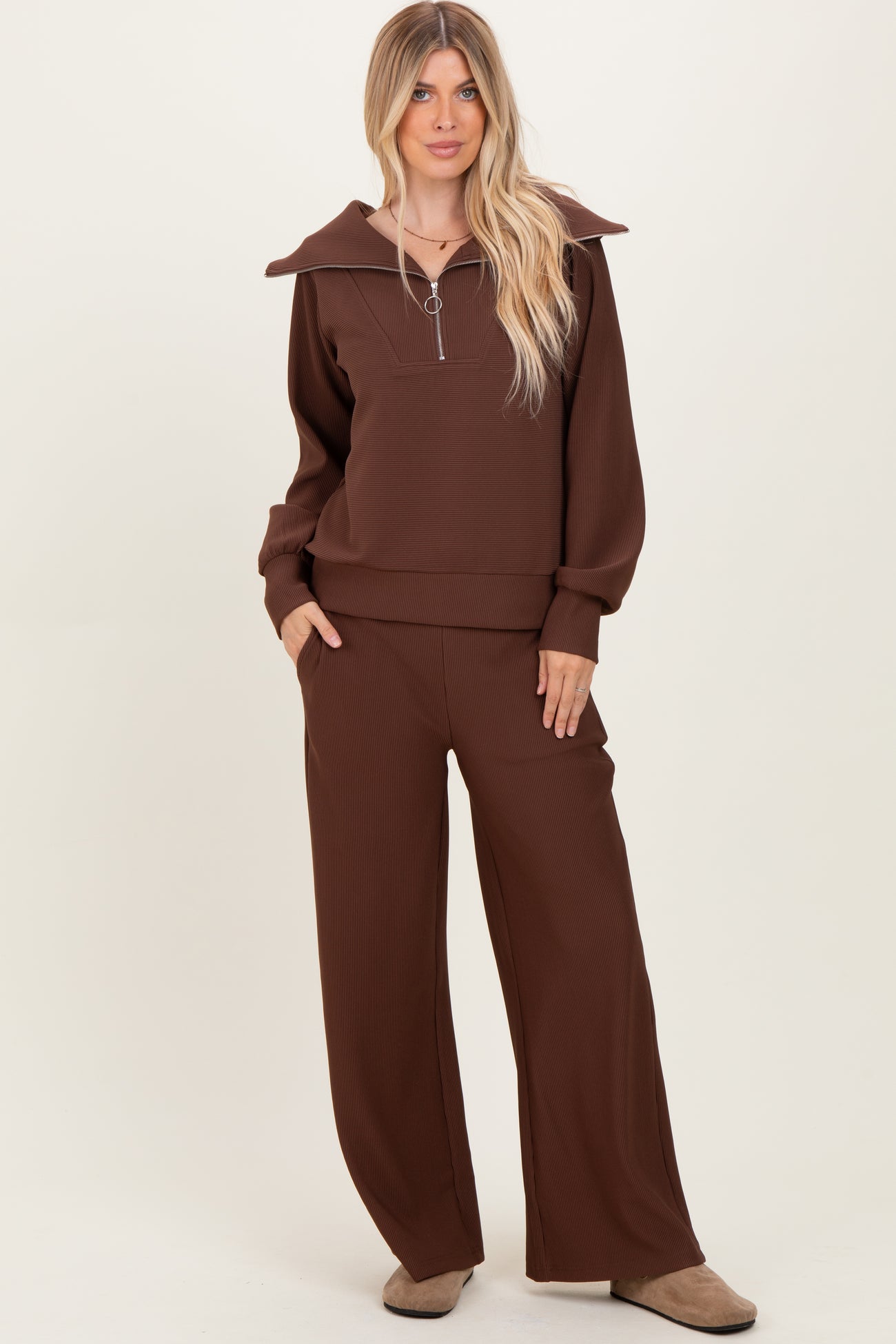 woman wearing a brown zip-up sweatshirt with a large collar and matching wide-leg pants