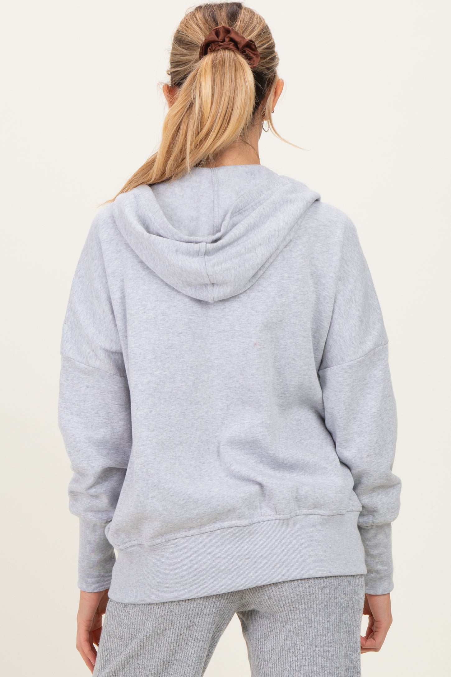 woman wearing a gray oversized maternity hoodie with a hood, seen from the back