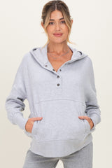 woman wearing a light gray maternity hoodie with a buttoned neck and front pockets