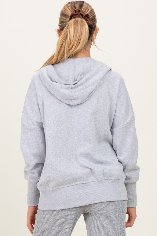 woman wearing a gray oversized maternity hoodie with a hood, seen from the back